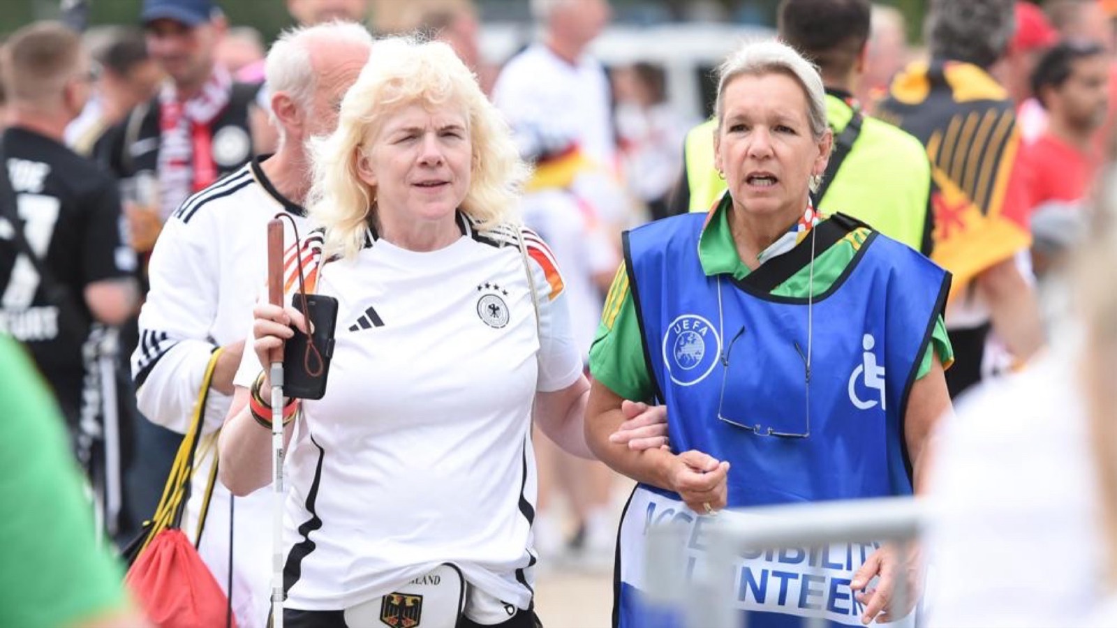 An accessibility volunteer guides a low-vision fan during the European Championship